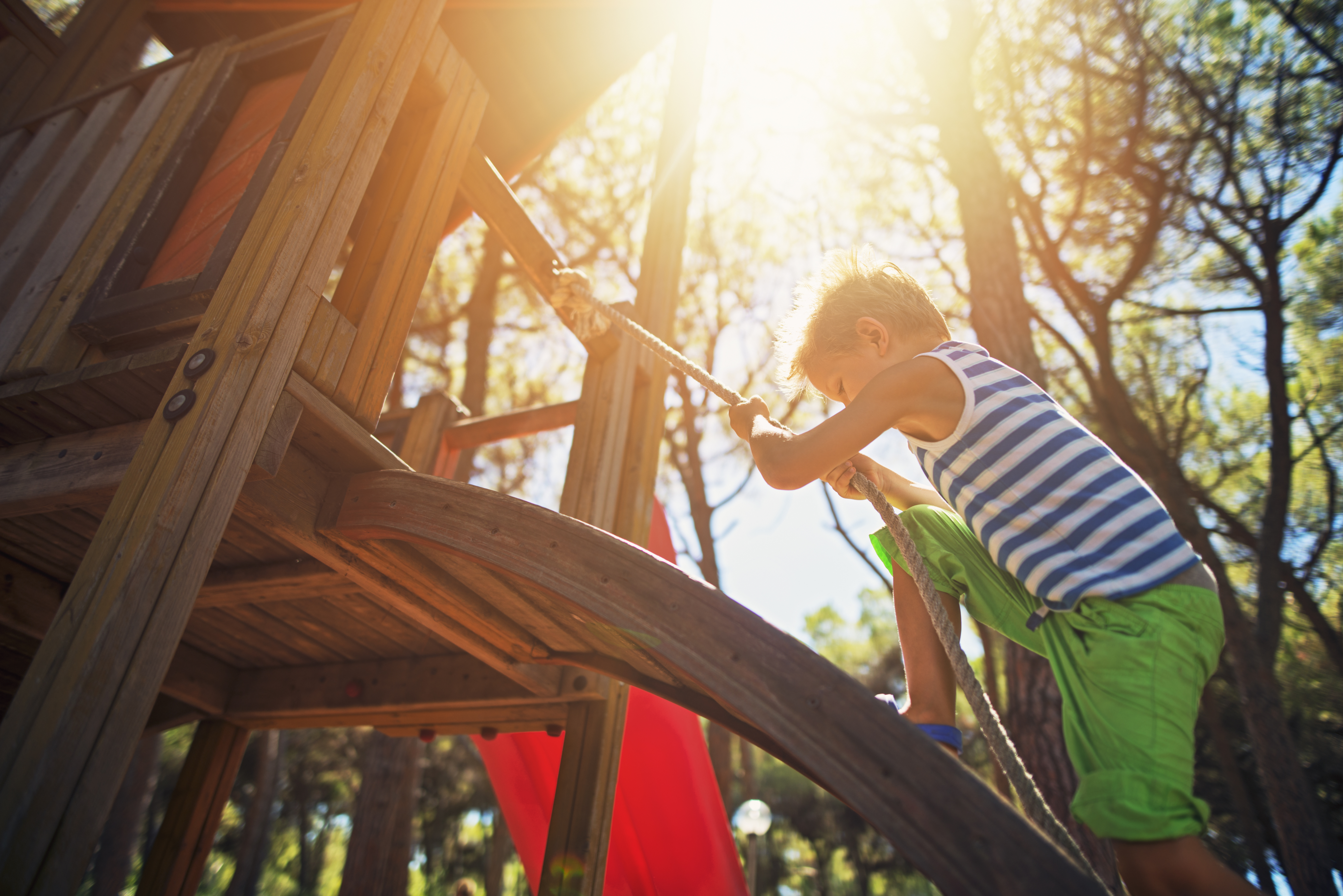 Kind spielt auf dem Kletterturm aus Holz im Garten